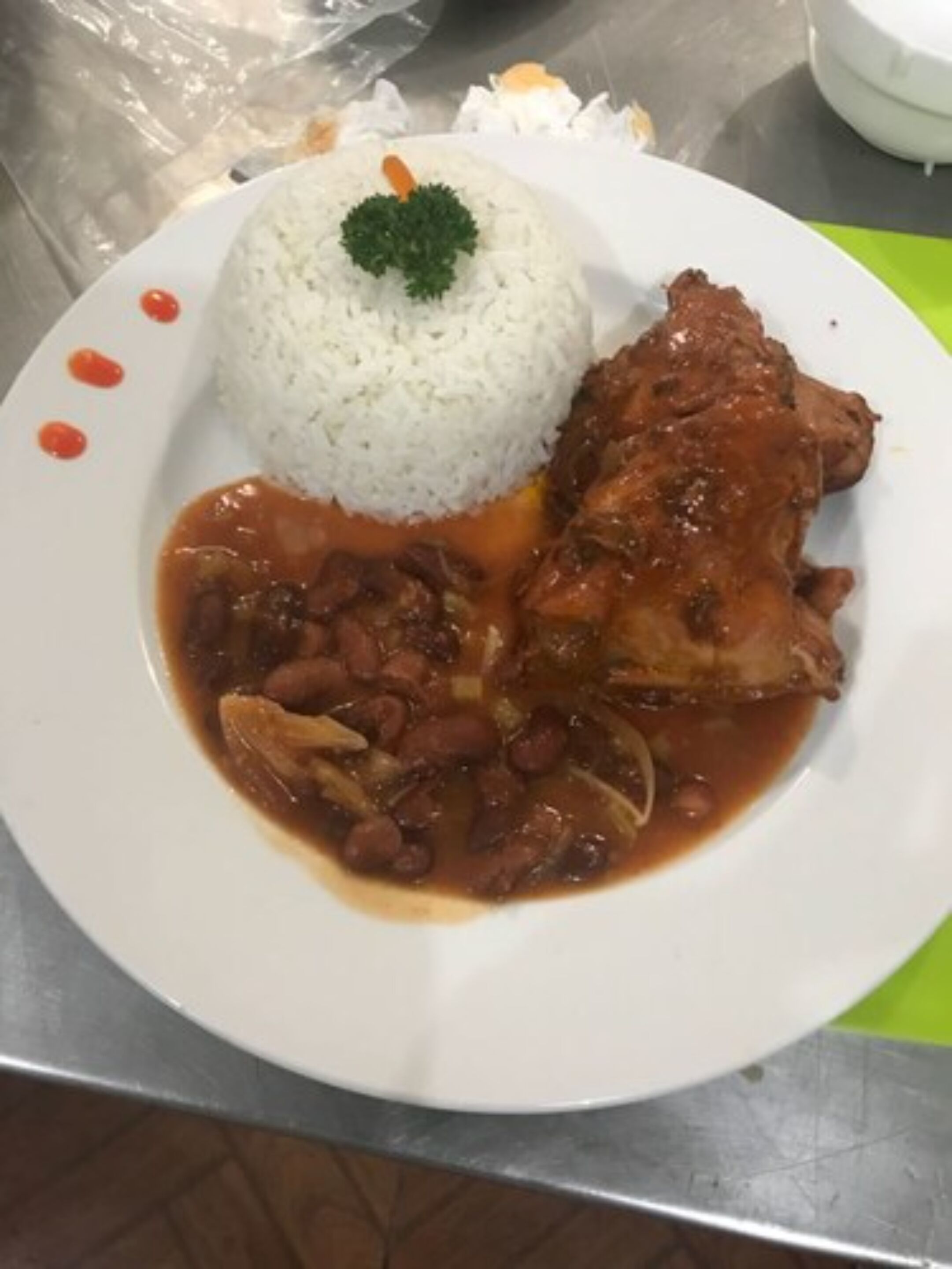 Un plato de arroz blanco, un trozo de carne y frijoles en salsa.