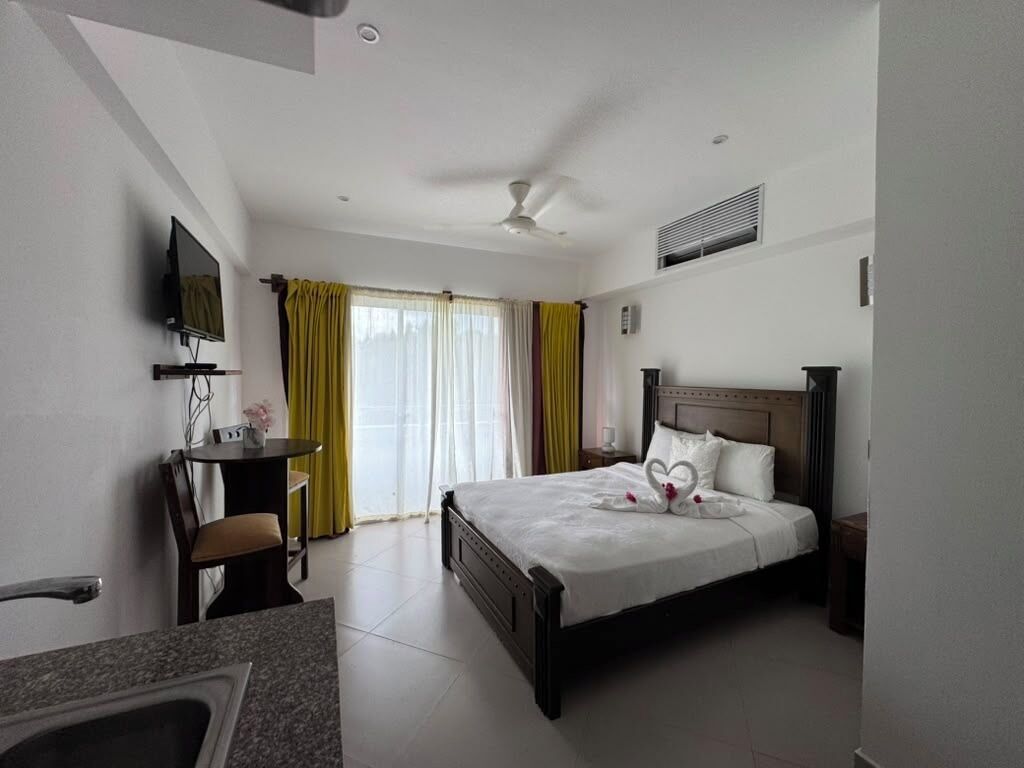 Una habitación de hotel con cama, escritorio, televisión y baño.