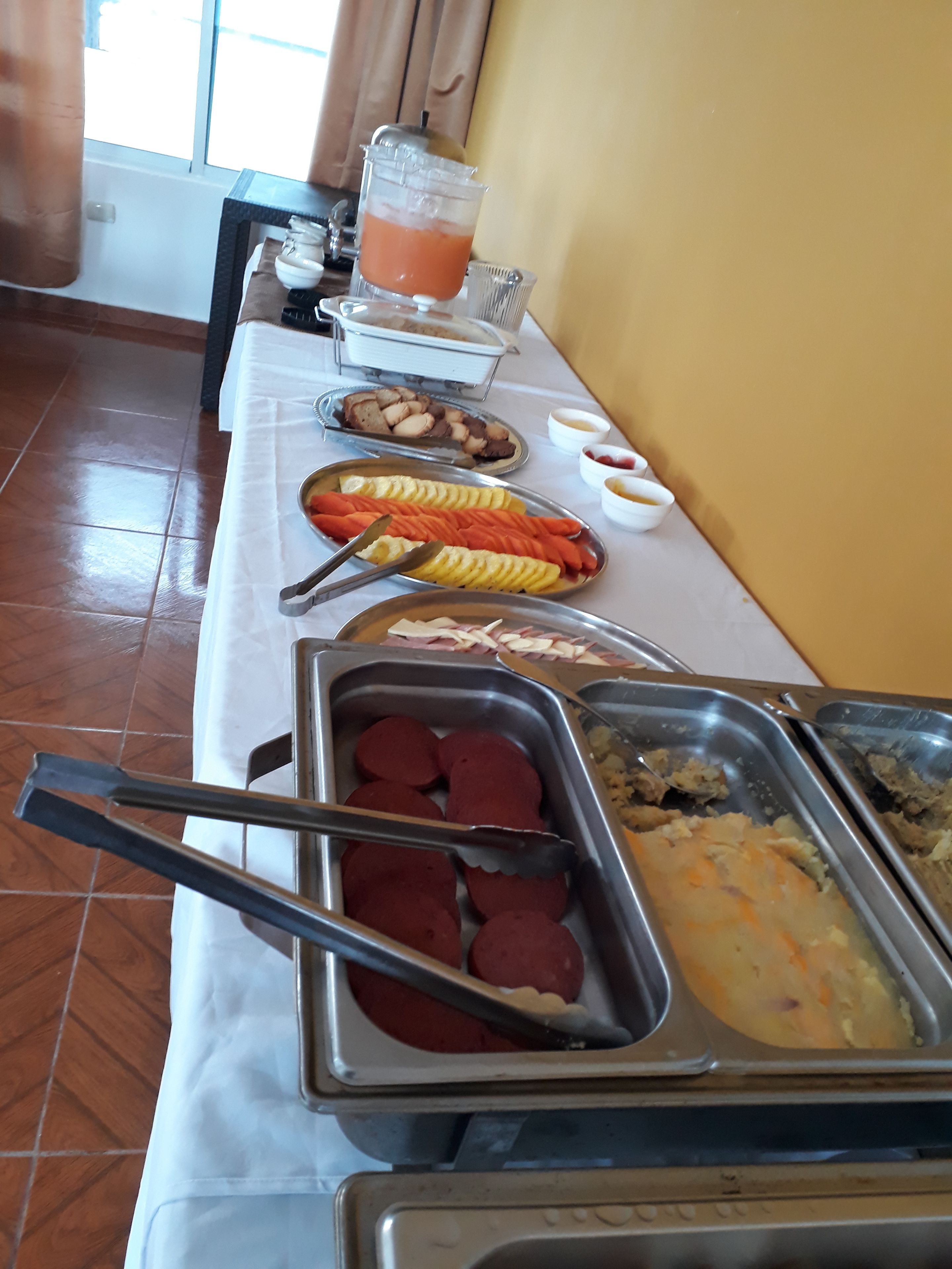 A buffet table with various food items and utensils.