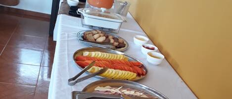 A buffet table with various food items and utensils.