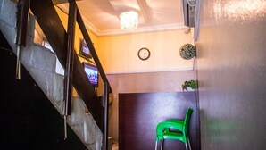 Een trap die leidt naar een kamer met een klok, een groene stoel en een televisie aan de muur.