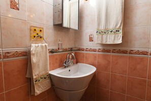 Un baño con lavamanos, espejo y toallero.