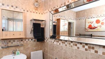 Un baño con lavamanos, inodoro y espejo.