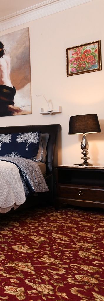 Ein Schlafzimmer mit einem Bett, einem Nachttisch, einer Lampe und einem Bild an der Wand.