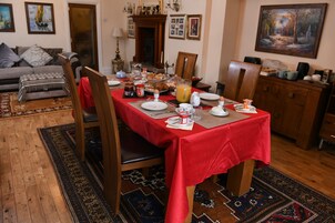 Comedor con mantel rojo, sillas de madera y una variedad de alimentos para el desayuno.