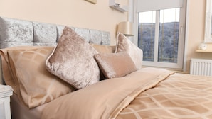 A neatly made bed with a patterned bedspread and multiple pillows. - Cilbrwyn Countryside Retreat (Swansea)