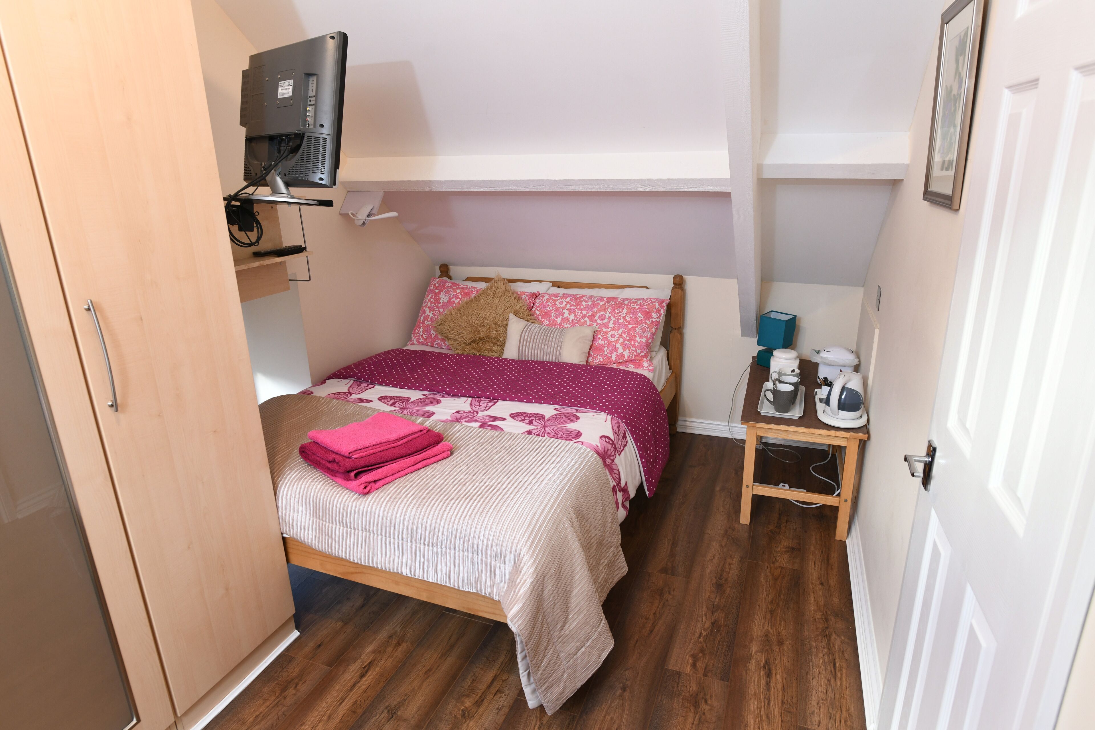 Un dormitorio con cama, una mesita de noche con hervidor y un armario.