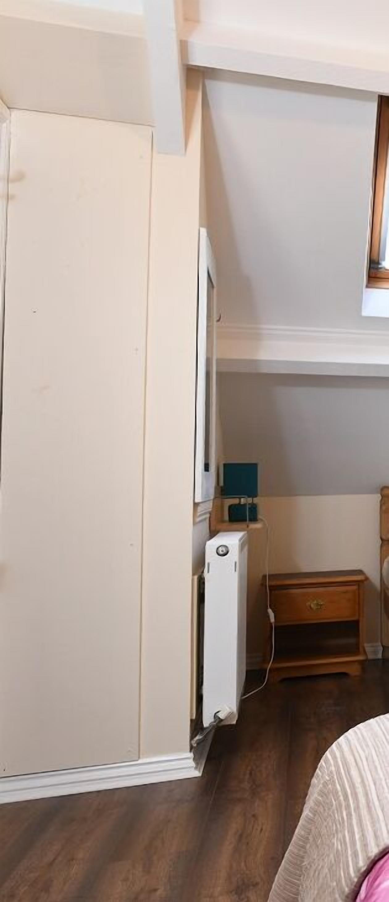 A bedroom with a bed, a dresser, a desk with a computer, and a window.