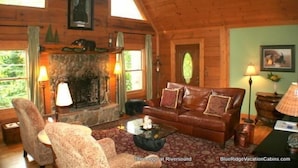 A cozy lodge room with a stone fireplace, leather sofa, and two armchairs. - Lodge at Riversound Apartment (Banner Elk)