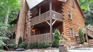 A log cabin with a balcony, surrounded by trees. - Lodge at Riversound Apartment (Banner Elk)