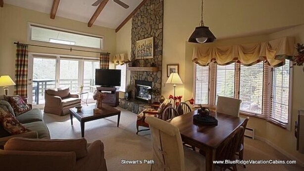 A spacious living room with a fireplace, a television, and a dining area. - Stewart's Path Apartment (Boone)