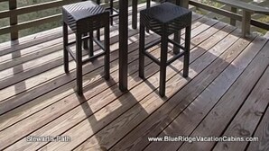 A covered outdoor deck with a table and two chairs, a skylight, and a view of trees. - Stewart's Path Apartment (Boone)