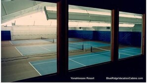 An indoor tennis court with a high ceiling and a view of the sky through a large window. - Stewart's Path Apartment (Boone)