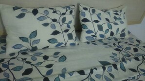 A bed with a leaf-patterned bedspread and matching pillows. - Hotel Les Graces (Abidjan)