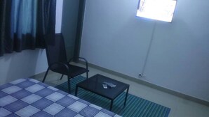 A small room with a bed, a chair, a table, and a window. - Hotel Les Graces (Abidjan)