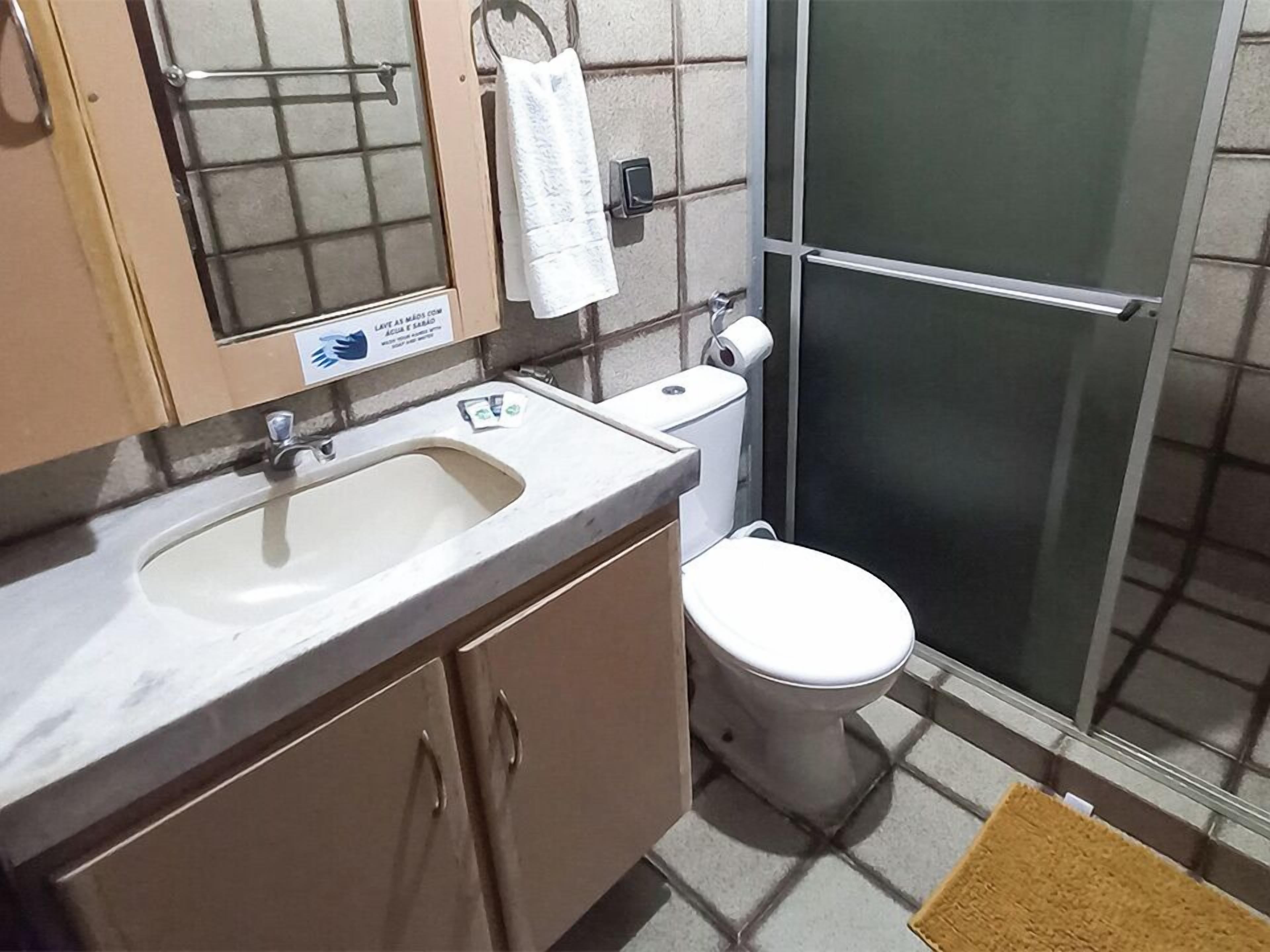 Un baño con lavabo, inodoro y una toalla colgada en la pared.