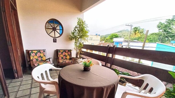 Un petit espace extérieur aménagé avec une table ronde et quatre chaises, un pot de fleurs et une roue décorative accrochée au mur.