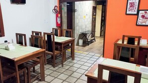 Un espace repas avec des tables et des chaises en bois, un extincteur et un revêtement de sol carrelé.