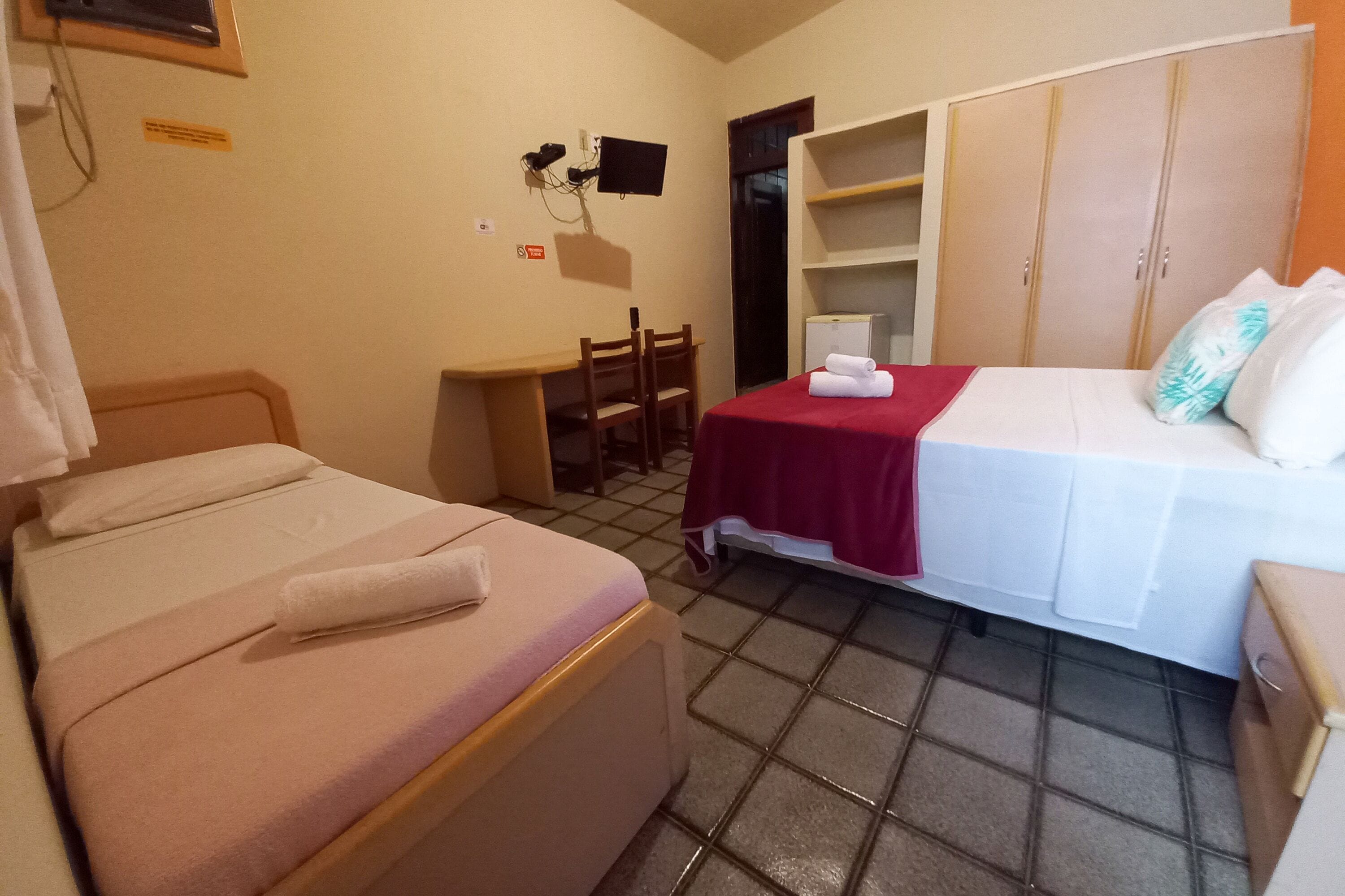 Een kleine, schone kamer met twee bedden, een bureau en een televisie.