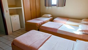 Une chambre avec deux lits, une armoire, un petit réfrigérateur et une fenêtre avec des rideaux.