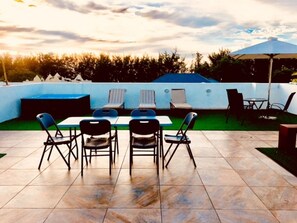 Un pati amb una taula i cadires, una piscina i gandules.