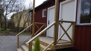 A wooden staircase leading to a red building with a white door. - Vänern Property apartments (Grums)