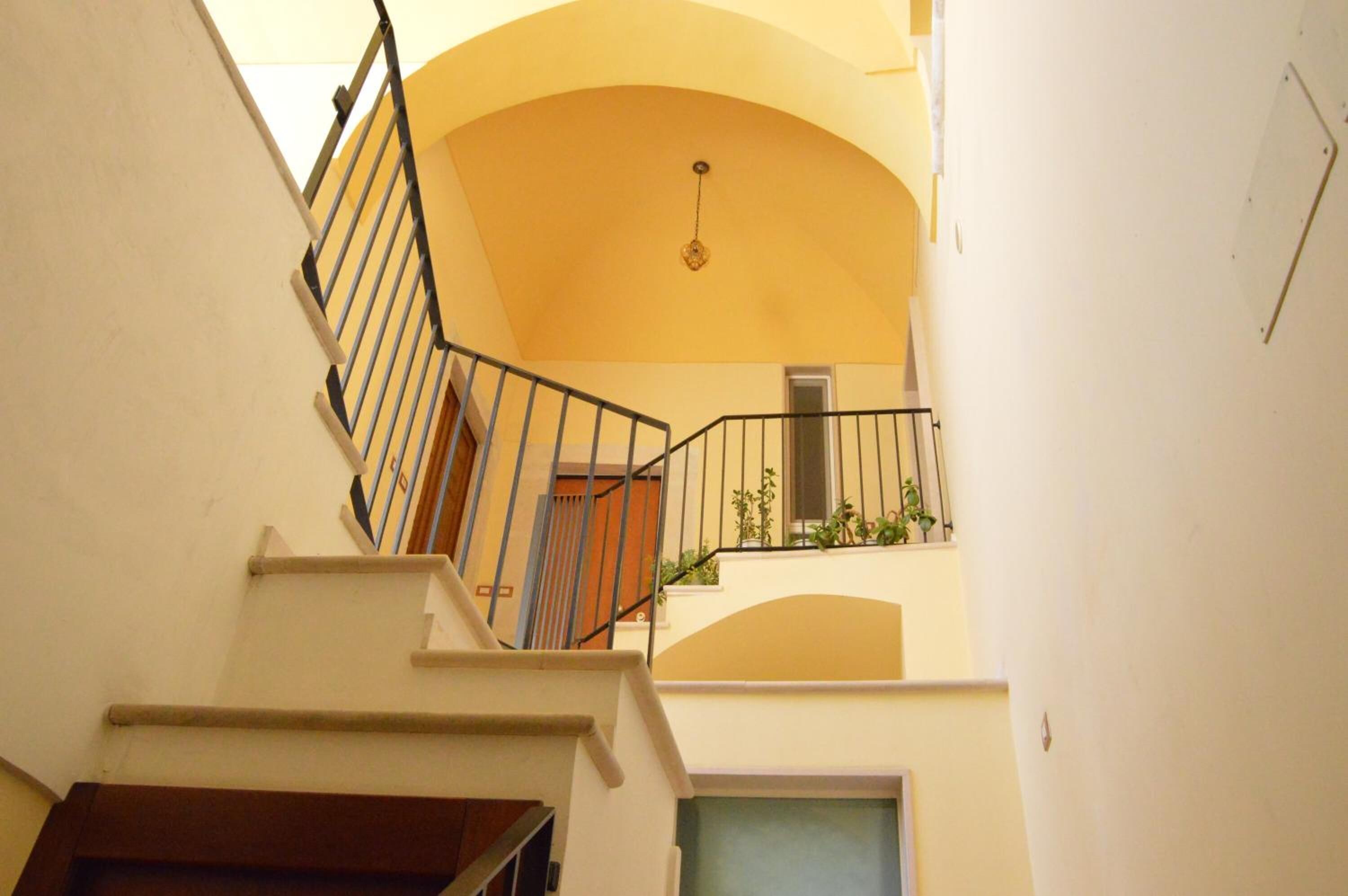 A staircase with a black railing leading to a balcony with plants.