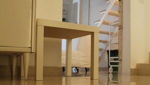 A room with a small table, a staircase, and a polished floor. - B&B Piazza Garibaldi (Santeramo in Colle)