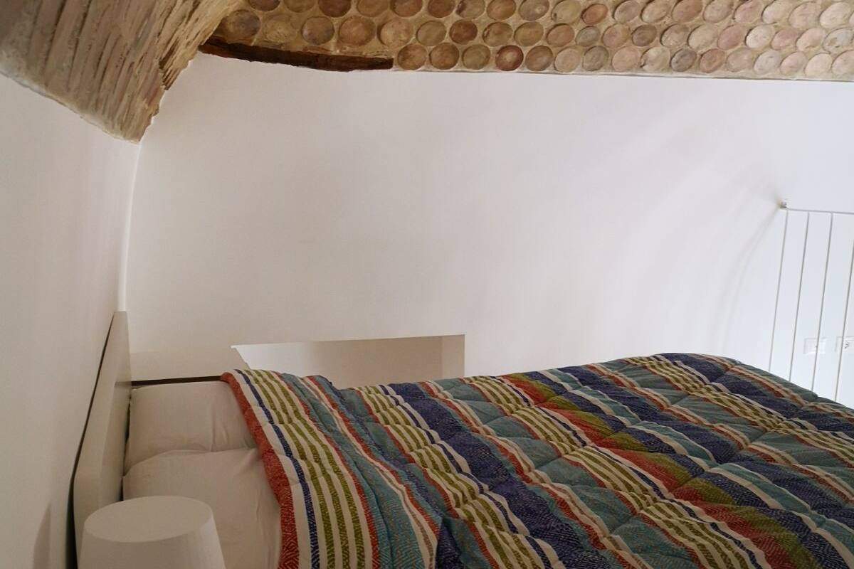 Une chambre à coucher avec un lit, une table de chevet et une lampe.