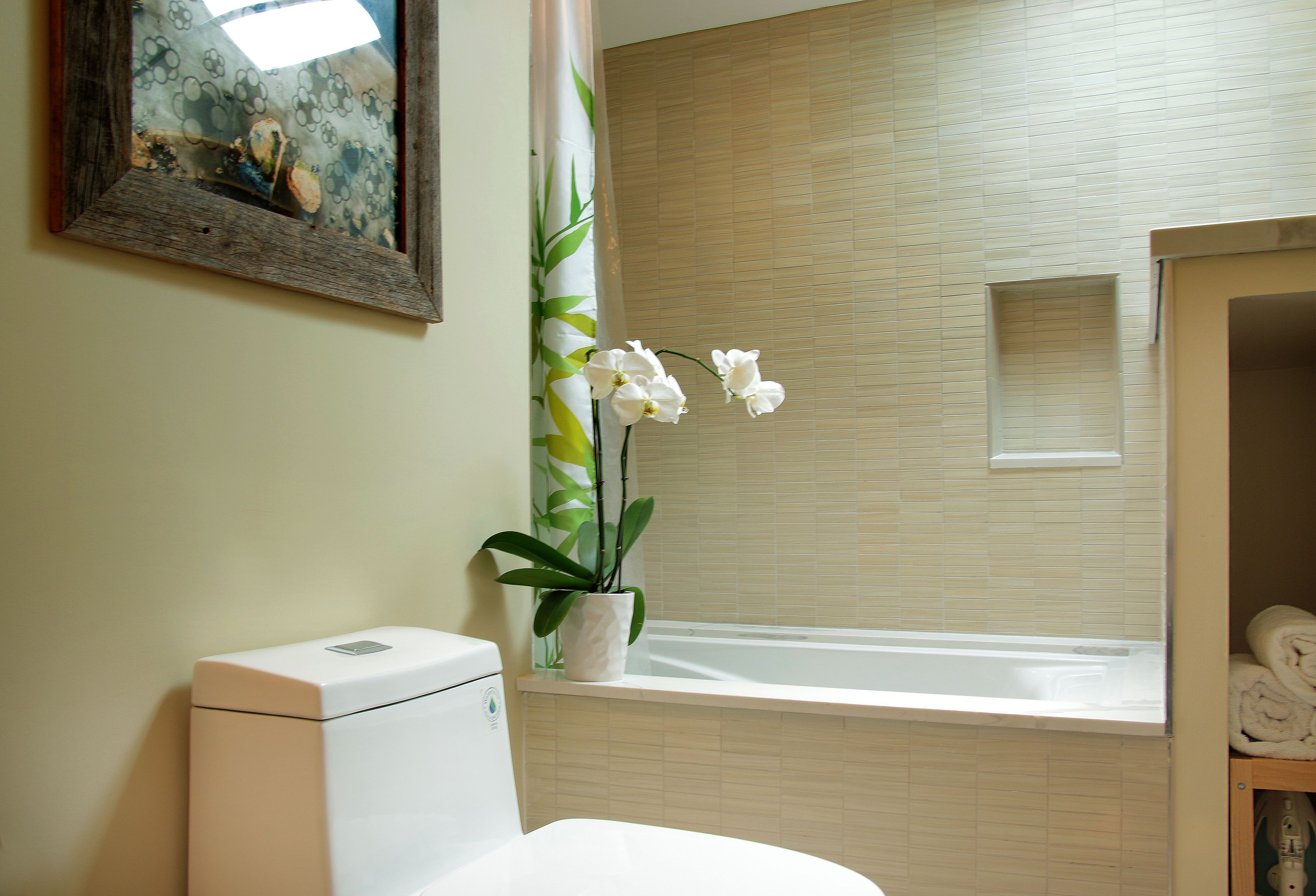 Un baño con inodoro, lavamanos, bañera y una orquídea en maceta.