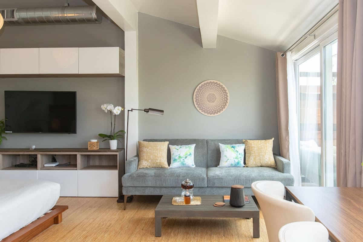 A modern living room with a grey sofa, a flat-screen TV, and a coffee table.
