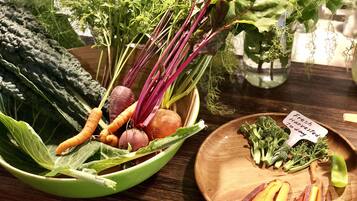 A wooden table with a variety of fresh vegetables including carrots, beets, and leafy greens.