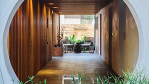 A corridor with wooden walls, a tiled floor, and a seating area with chairs and a table. - Inn at Moonlight Beach (Encinitas)
