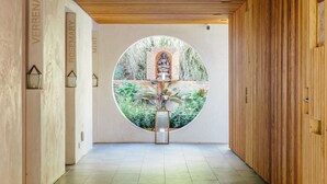 A hallway with a circular window featuring a statue, surrounded by labeled columns and a wooden wall. - Inn at Moonlight Beach (Encinitas)