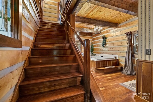 A wooden staircase leading to a bathroom with a bathtub and a shower area. - Cinnamon Valley Resort (Eureka Springs)