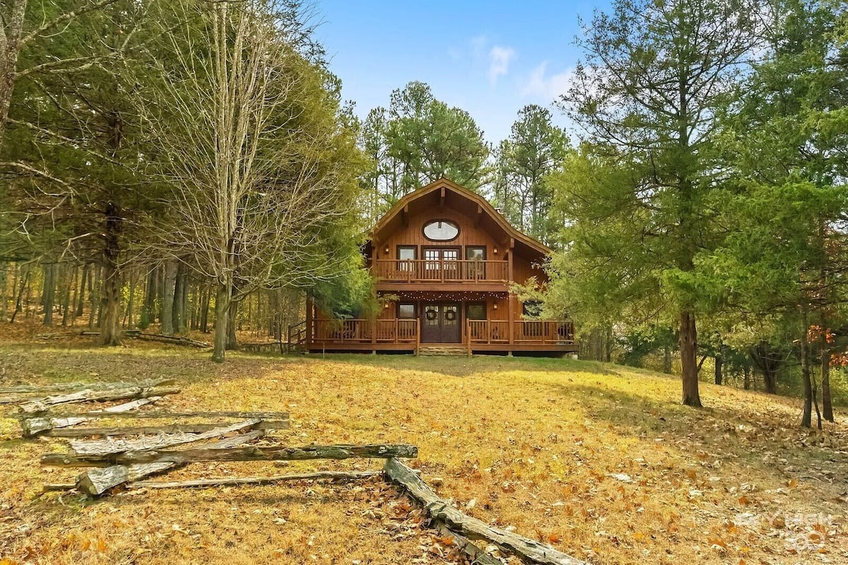 A cabin with a front porch, surrounded by trees.
