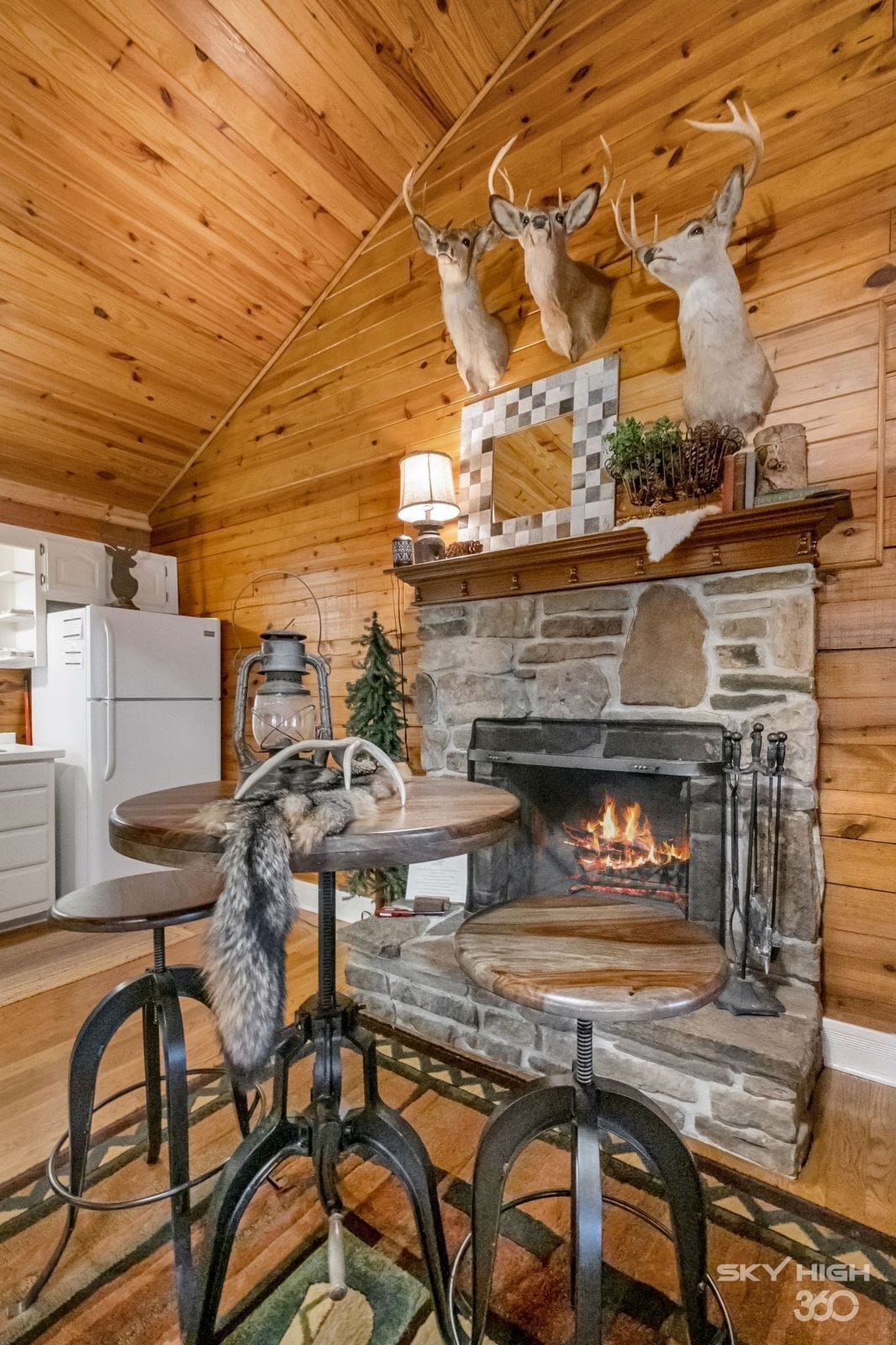 Un interior acogedor de cabaña con chimenea de piedra, techo de madera y ciervos montados.