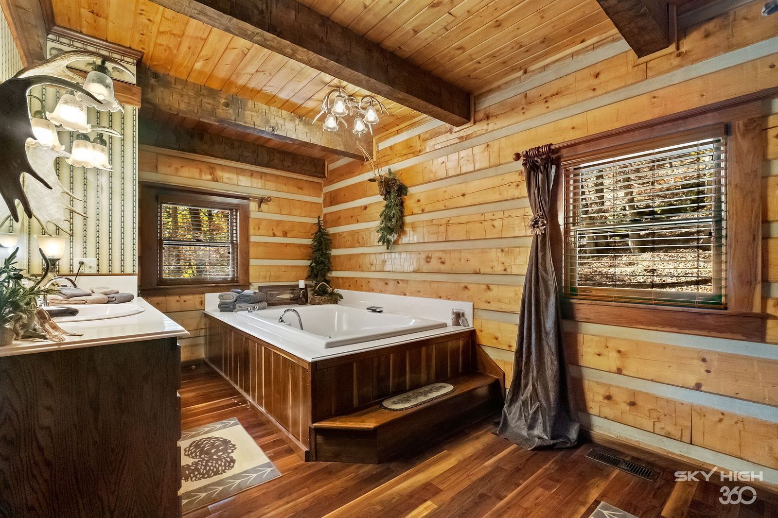 Interior de una cabaña con detalles de madera, una bañera grande, un lavabo y una zona de ducha.
