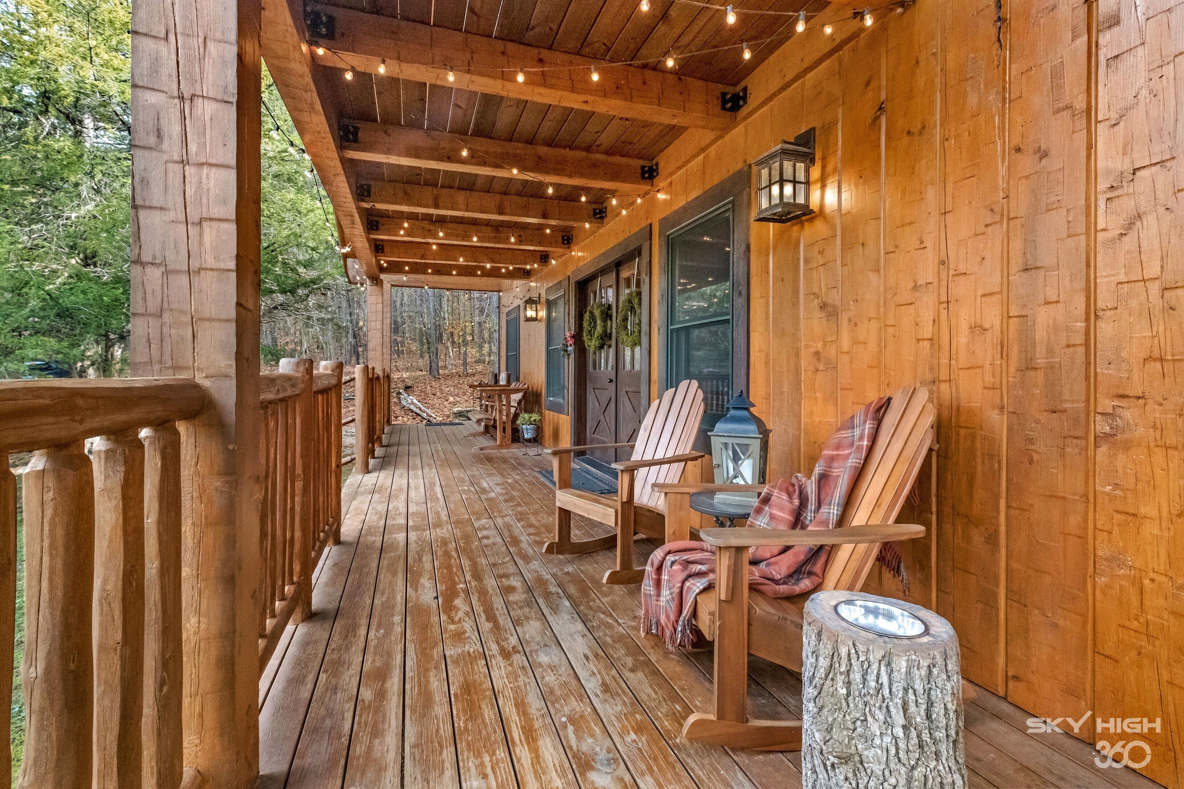 A wooden deck with a railing, chairs, and a table.
