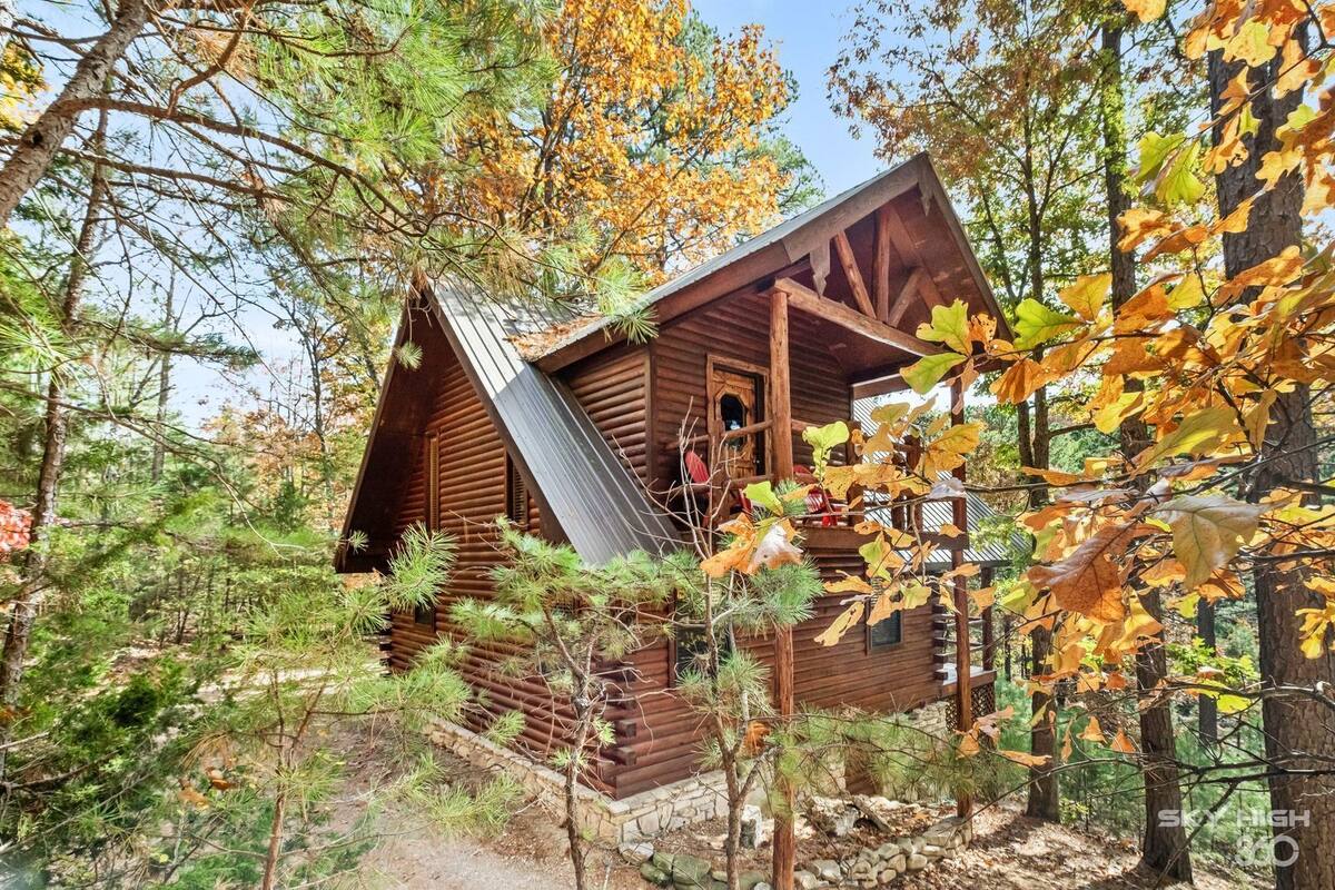 A cabin surrounded by trees with a wooden exterior and a metal roof.