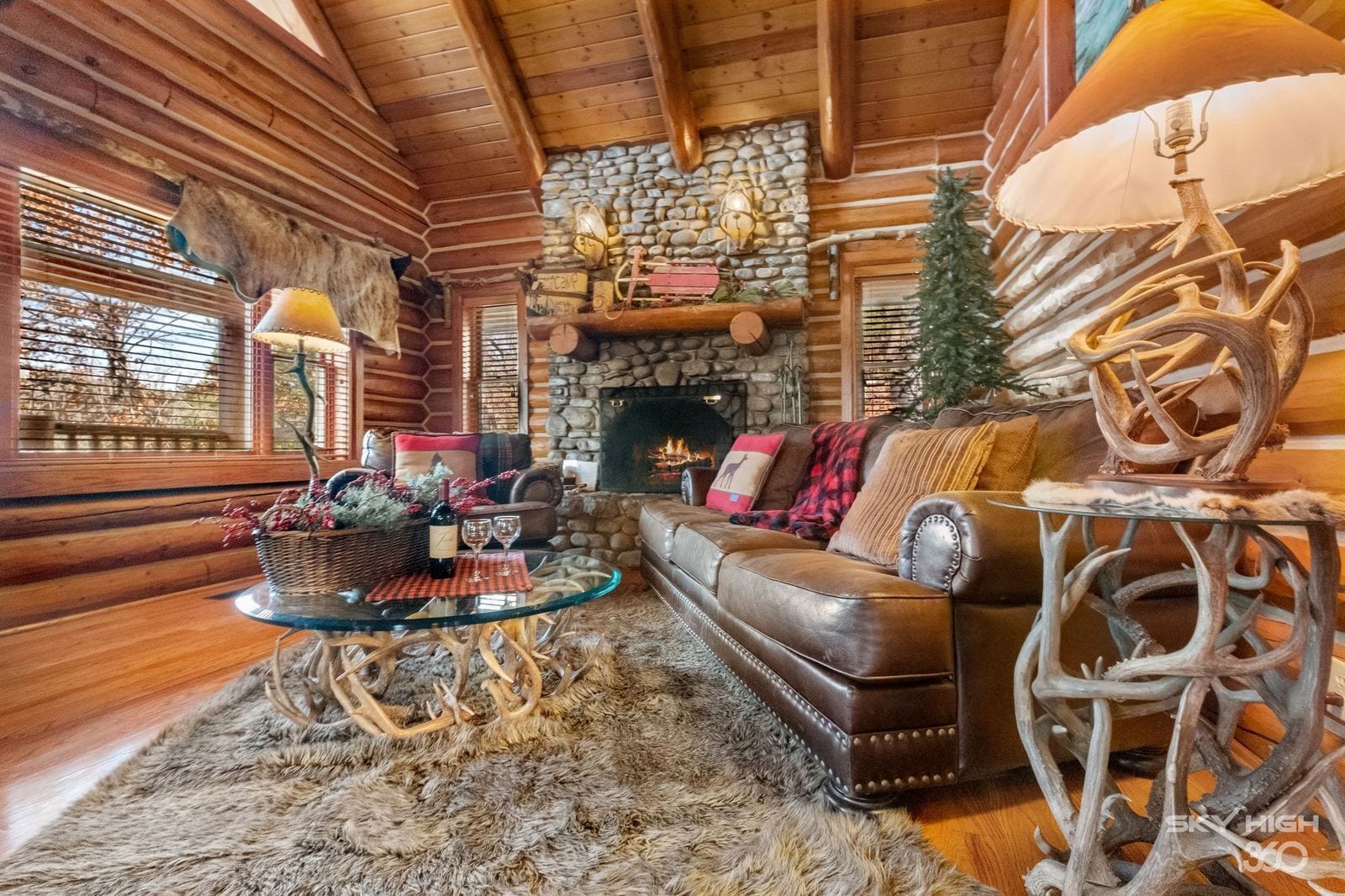 Un intérieur chaleureux de chalet en bois avec une cheminée en pierre, un canapé en cuir et un décor rustique.