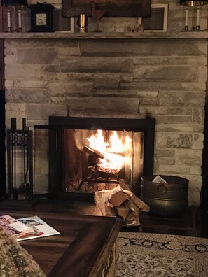 Cozy living room with a fireplace, coffee table, and decorative stand.