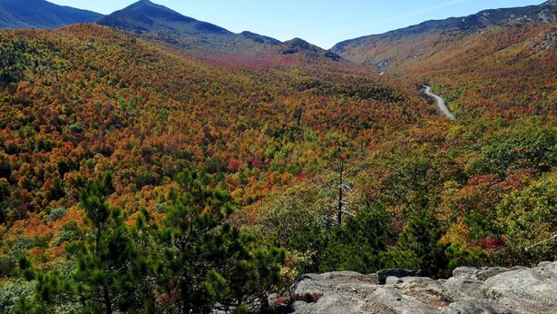 A mountainous landscape with autumn foliage and a winding road. - Lake Placid Home in the Heart of Adirondack Village
 (Lake Placid)