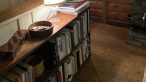 A cozy log cabin interior with a wooden bookshelf, a lamp, and decorative mirrors. -  Charming, Eco-Friendly Cabin Retreat, Heart of Deep Creek (Oakland)