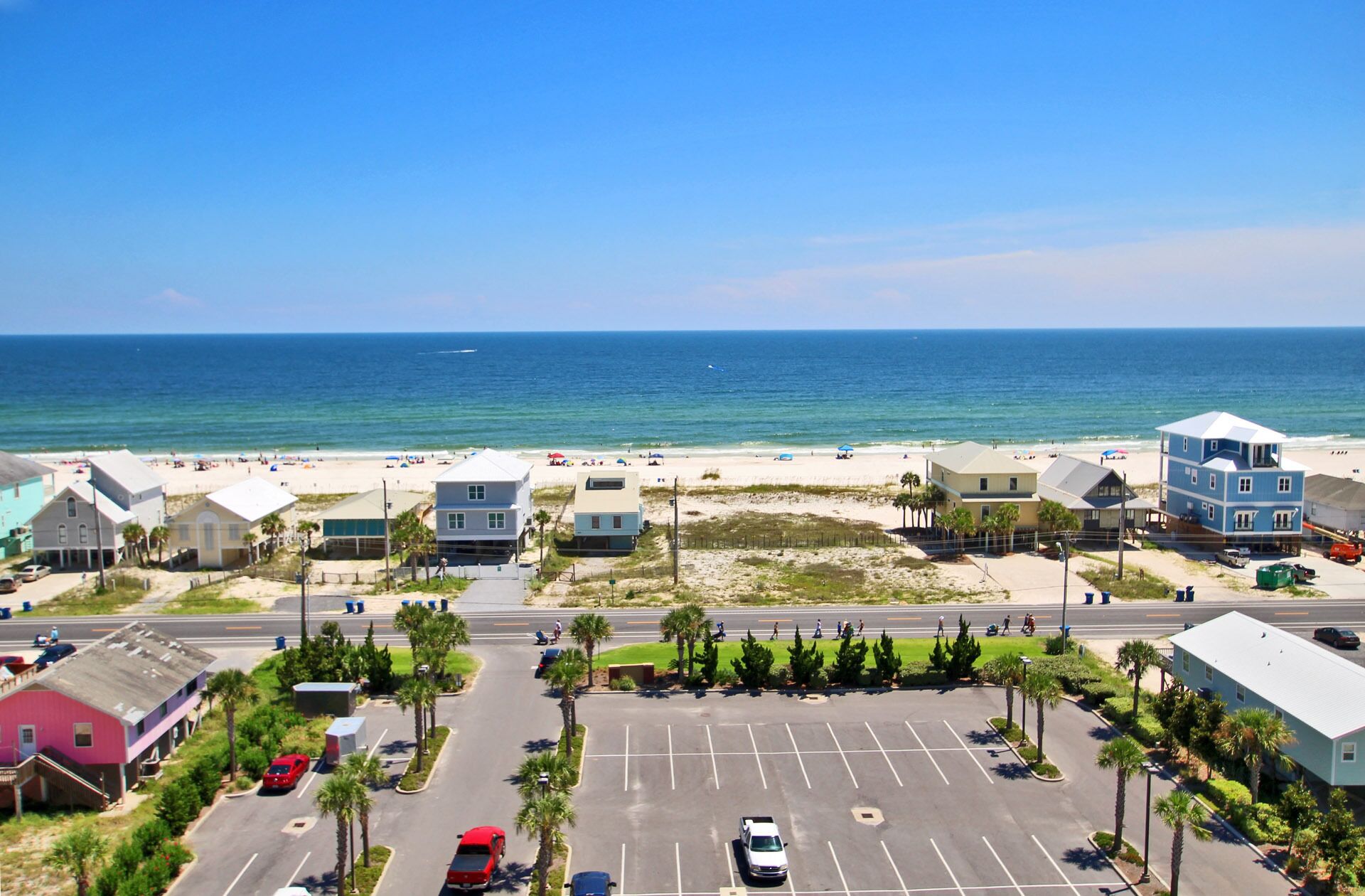 A coastal view with a parking lot, beach, and buildings.