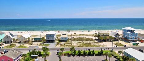 A coastal view with a parking lot, beach, and buildings.
