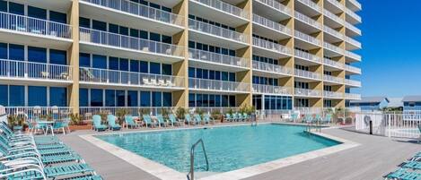 A hotel with a large pool area, multiple balconies, and sun loungers.
