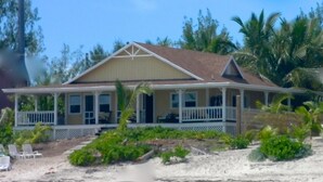 Une maison située en bord de mer, dotée d’une véranda, d’une piscine et d’une plage de sable.