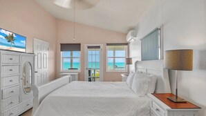 Une chambre à coucher avec un lit, une commode et une vue sur l’océan par les fenêtres.