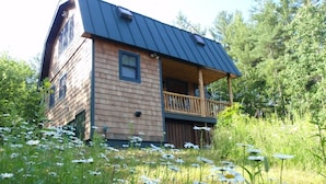 Een houten chalet met balkon, omringd door een veld met margrieten.